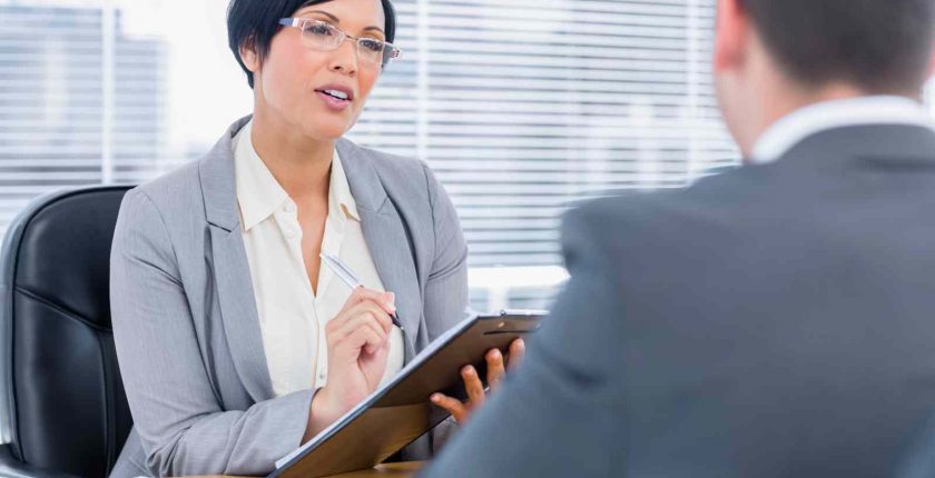 A female hiring manager asks competency-based questions during an executive-level interview